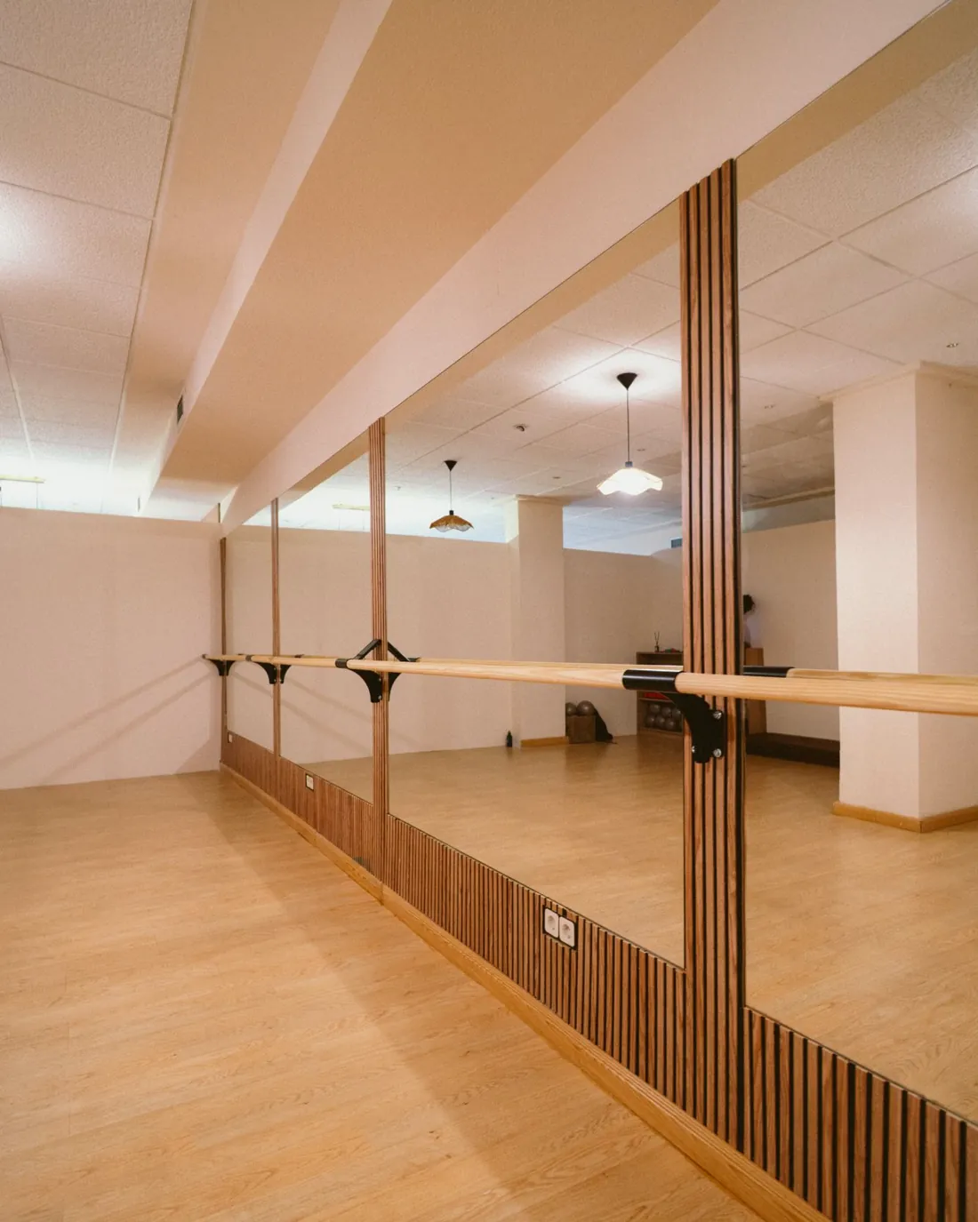 La sala de Barre de THE LAB, con la barra de madera y los espejos de pared